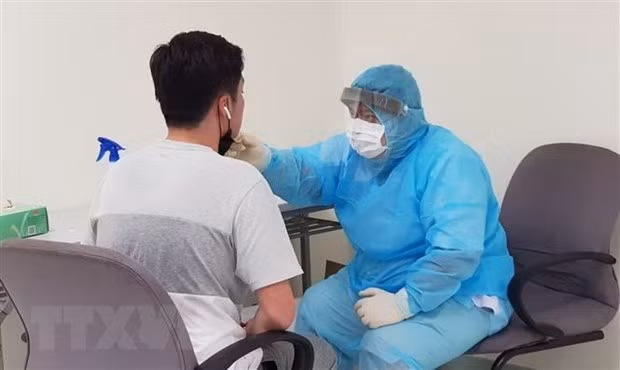 A medical worker gives check-up to a people entering Vietnam from another country at Tan Son Nhat International Airport in Ho Chi Minh City (Photo: VNA)
