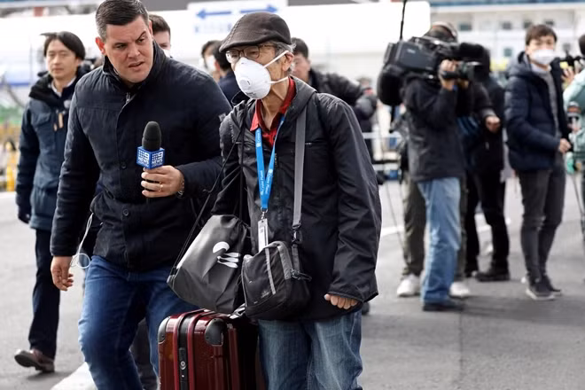 A member of the media approaches a passenger after he walked out from the cruise ship Diamond Princess at Daikoku Pier Cruise Terminal in Yokohama, south of Tokyo, Japan February 19, 2020. REUTERS/Athit Perawongmetha