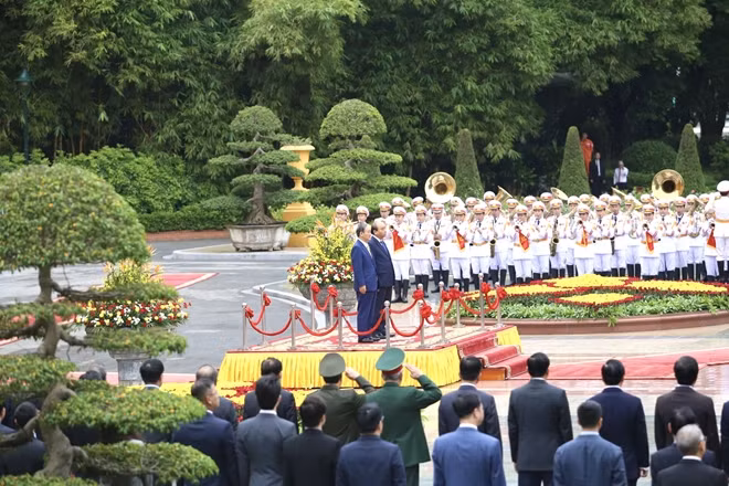 Prime Minister Nguyen Xuan Phuc and Japanese Prime Minister Yoshihide Suga on podium of honour, listening to Vietnamese and Japanese anthems