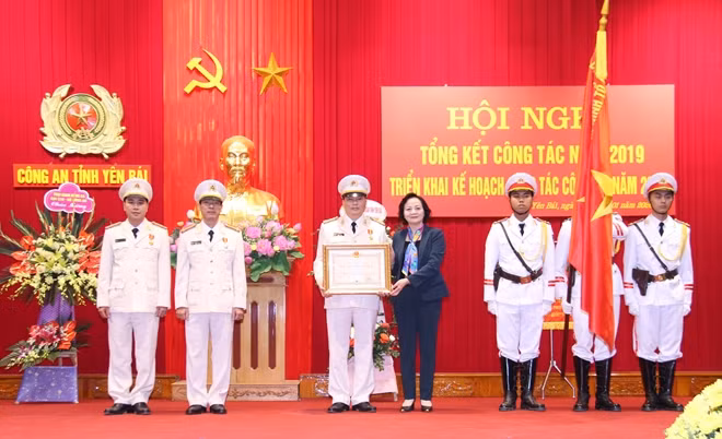 Under the authority of the State President, Ms. Pham Thi Thanh Tra hands the Third-class National Protection Order to the Logistics Office under the Yen Bai Provincial Police Department.