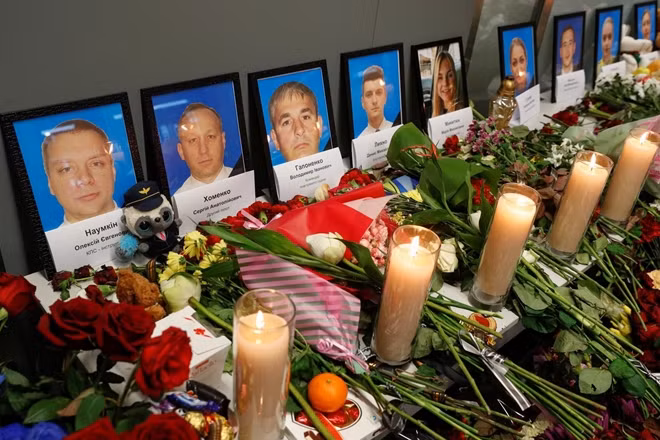 Flowers and candles are placed in front of the portraits of the flight crew members of the Ukraine International Airlines Boeing 737-800 plane that crashed in Iran, at a memorial at the Boryspil International airport outside Kiev, Ukraine January 11, 2020. REUTERS/Valentyn Ogirenko