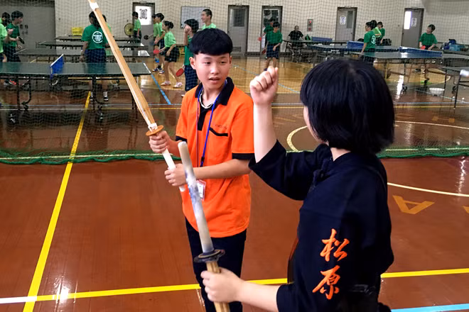 Children interacting with Japanese students by playing Kendo, a Japanese traditional sport