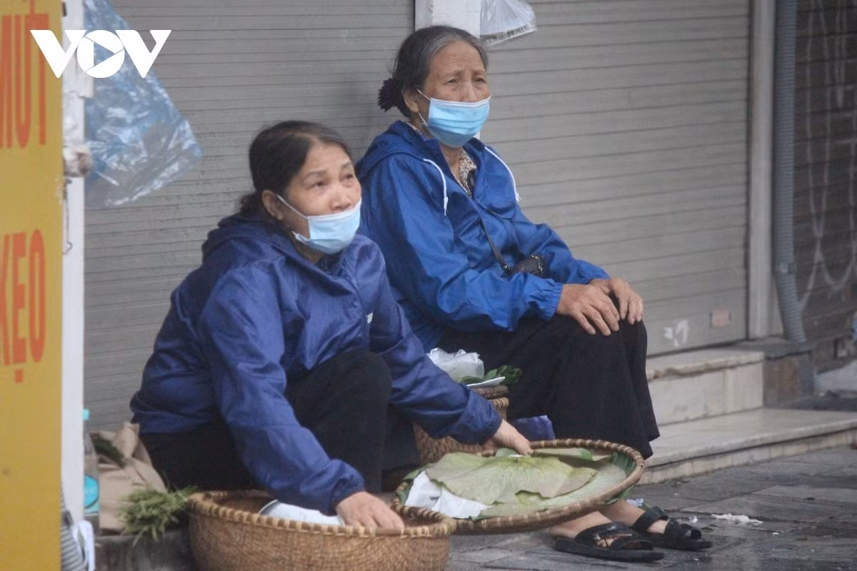 Street vendors seek shelter in front of shops in Hanoi’s Old Quarter amid the cold air and rainy conditions.