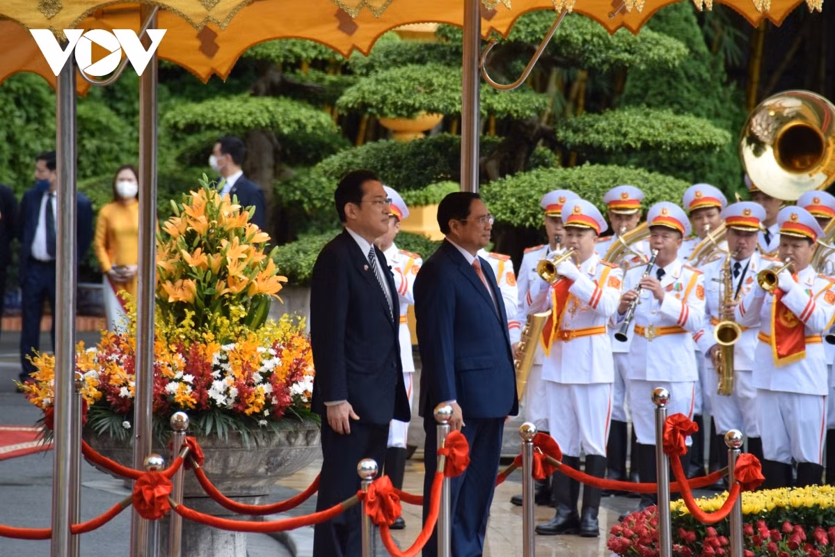 PM Chinh invites his Japanese counterpart to step on the podium while military bands play the national anthems of both Vietnam and Japan.