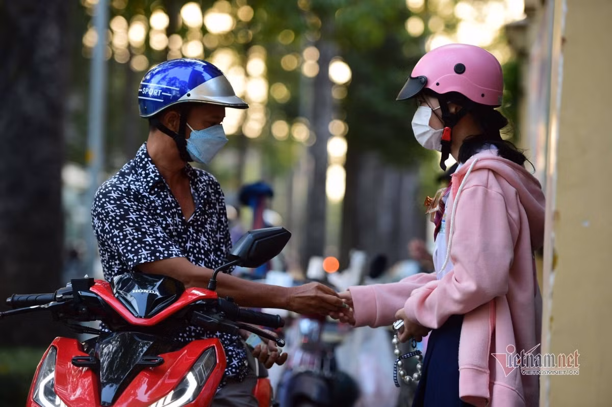 HCM City high schools reopen after half a year of closure due to COVID-19 ảnh 1 Many students are taken to school on the back of their parents’ motorbikes, while some others choose to cycle instead.