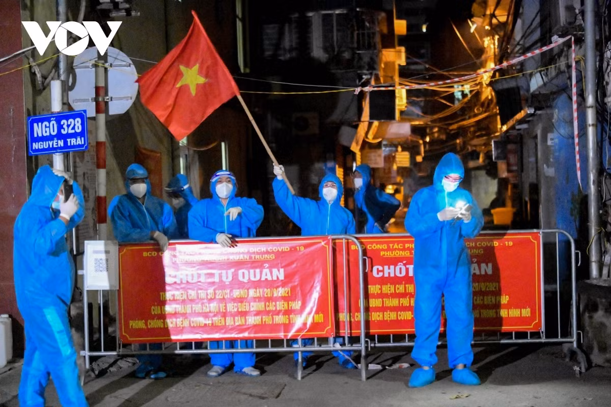 Locals wave the national flag and show their joy at the isolated area being removed lockdown on September 29.